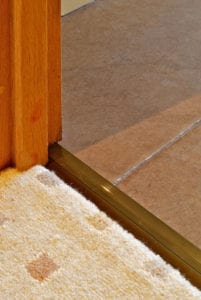 Posh door thresholds fitted between patterned beige carpet and tiles