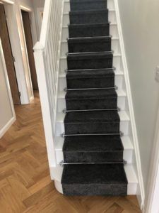 Brushed chrome stair rods with Sphere finials on blue carpet & white staircase