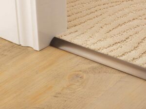 ribbed carpet joined to vinyl wood look floor with bronze coloured door threshold
