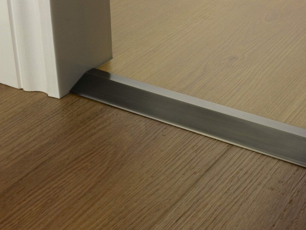 Premier Ramp 12mm sloping door threshold, shown from laminate to vinyl in pewter