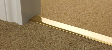 Polished brass carpet to carpet door bar joining two brown carpets in doorway