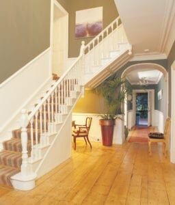 Grand white painted staircase fitted with striped runner and wooden Tudor stair rods