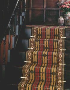 Period dark wood staircase fitted with tartan stair runner & Victorian brass stair clips
