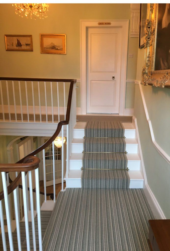 Polished brass stair carpet rods on striped runner, sweeping stairs