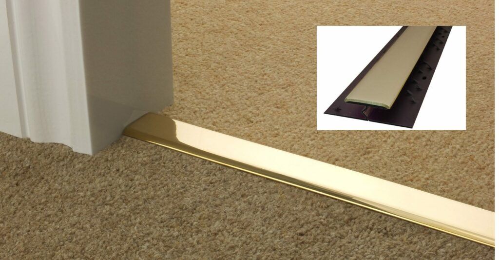 Carpet to carpet threshold in polished brass shwon joining a brown tufted carpet