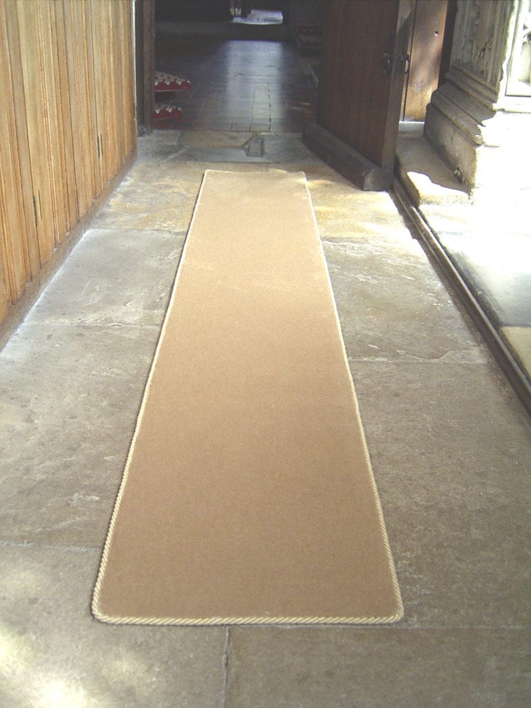 Beige rug with carpet binding tape arpound edge on church floor