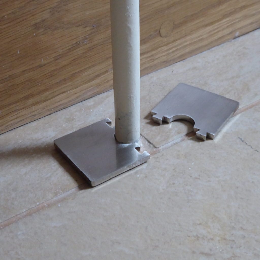 Oblong pipe collar clips together around the radiator pipe on the tiled floor