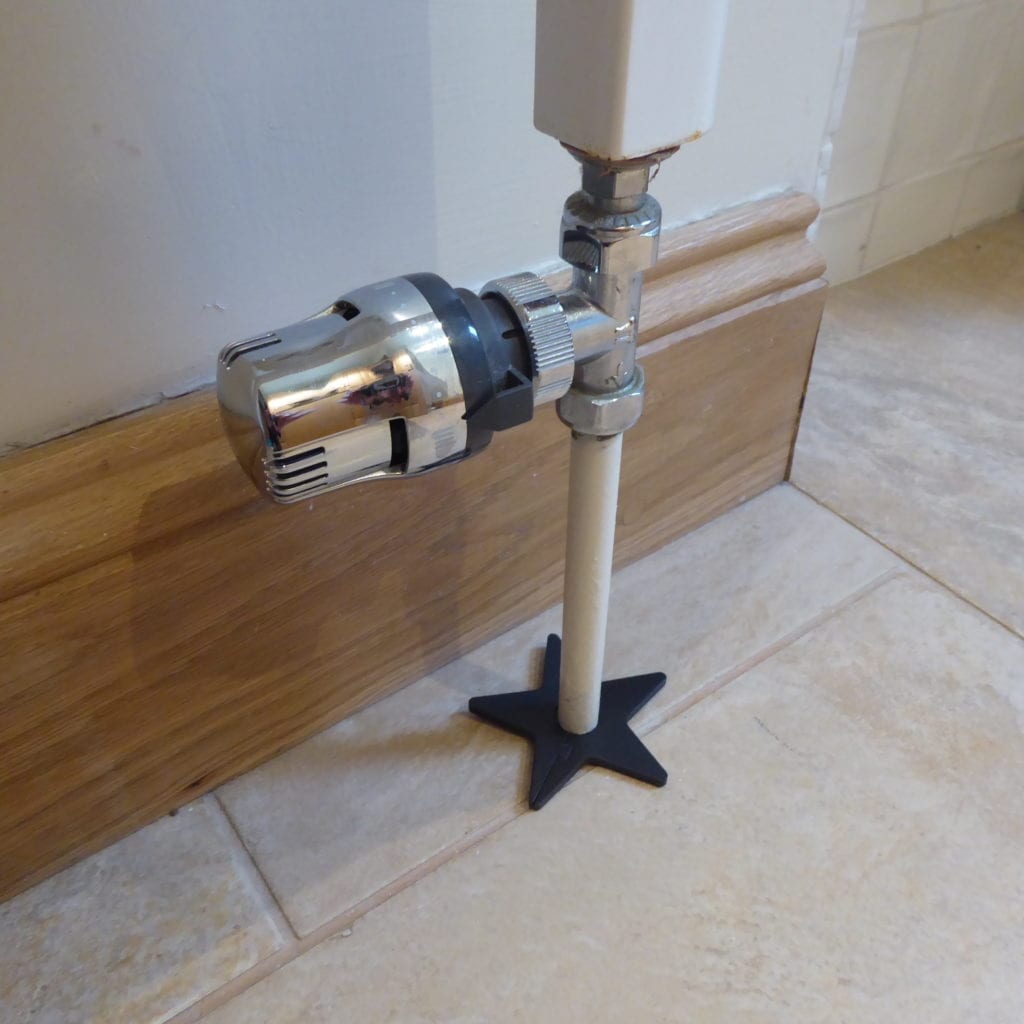 Black star-shaped pipe collar to cover up gap around pipe in floor